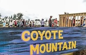 15_original People stand on a platform above a sign reading 'Coyote Mountain.'